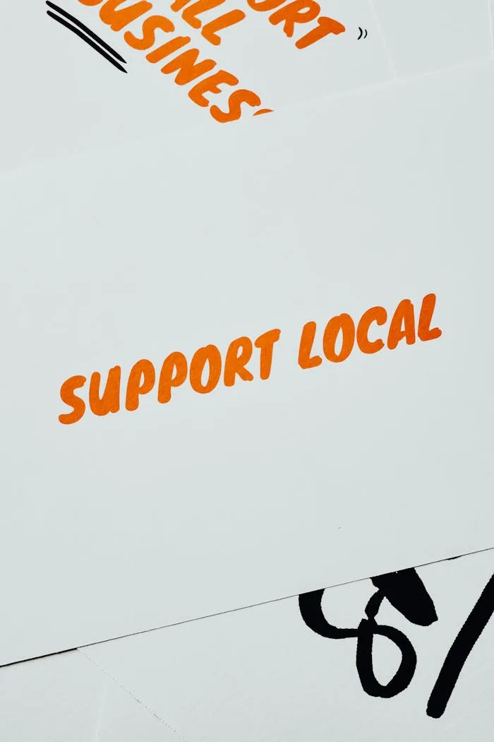 vision A minimalist card displaying 'Support Local' in bold orange text on a white background, promoting small businesses.